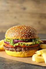 Burger with delicious patty and french fries on table