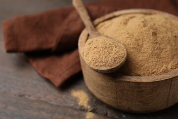 Dietary fiber. Psyllium husk powder in bowl and spoon on wooden table, closeup. Space for text