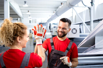 Production line workers high-five gesture in factory. 