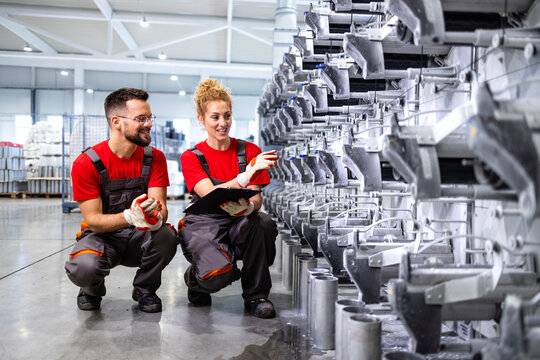 Mechanical engineers checking parts and productivity of new assembled machine inside the factory.