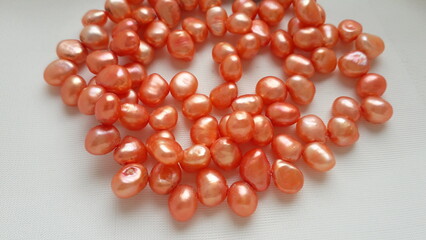 Pink, coral natural pearls on a white light background. Pearl beads, necklaces, beads. Natural...