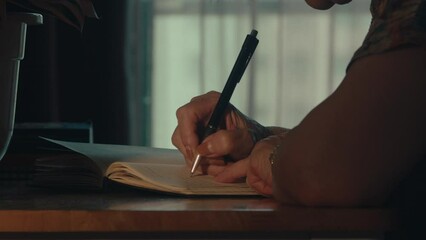 woman lady sitting alone in house room writing with ink pen on book notebook journal inspirational creative idea , close up