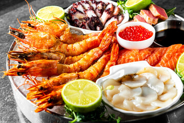 Assorted seafood including grilled shrimp, sliced salmon, and octopus, served with lemon slices and sauces, presented in a visually appealing manner