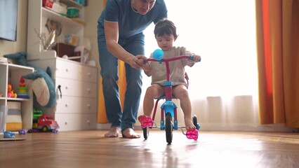 father teaches son baby to ride a bike. happy family childhood dream concept. father and little son...