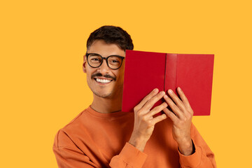 Man covering face with book and smiling