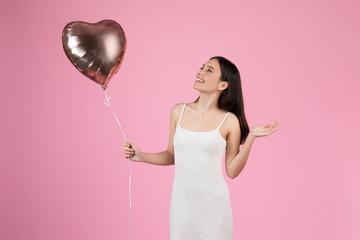 Solo heart-shaped balloon in woman hand on pink background