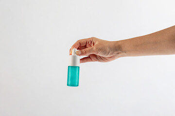 Blue glass cosmetic bottle in hand, Skin care or sunscreen cosmetic on white background.