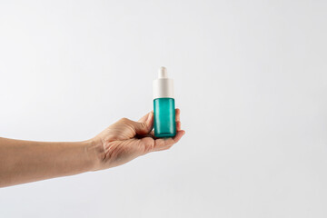 Blue glass cosmetic bottle in hand, Skin care or sunscreen cosmetic on white background.