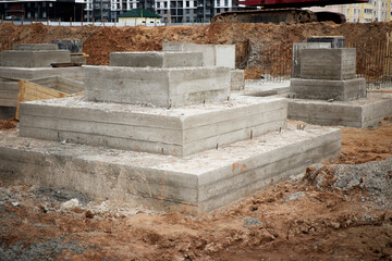 A group of cement blocks lies still on a dirt field, waiting patiently to be used in the...