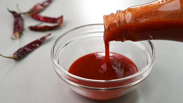 Pouring red chilli sauce in a bowl.
