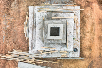 A square of wood delicately balances on a concrete slab, showcasing the contrast between natural...