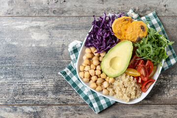 Healthy salad with avocado,lettuce,tomato and chickpeas on wooden table. Top view. Copy space