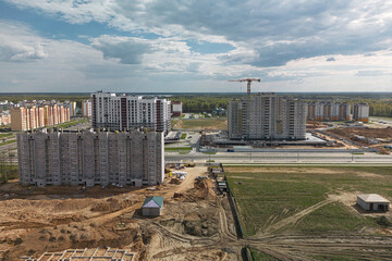 An aerial view captures a sprawling, tall building under construction, with cranes lifting...