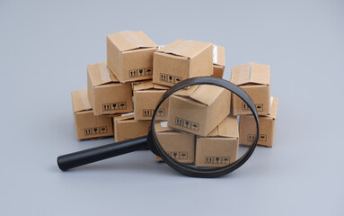 Review goods, taxes and shipping concept. Many carton boxes under magnifying glass.