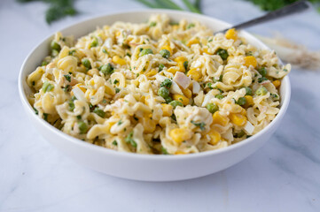 Low fat and high protein  pasta salad with chicken breast, geen peas, corn and herbs in a bowl