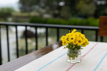 Selective focus yellow chrysanthemum In a small glass pot placed on a white table. There is space for text. - Powered by Adobe