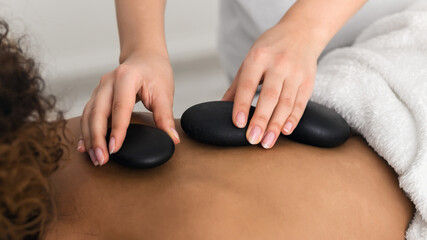 Masseur placing stone on back of woman