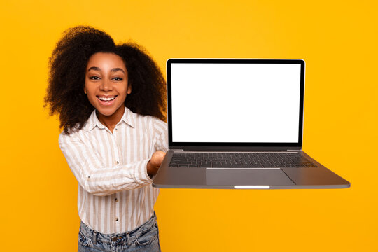 Young woman presenting laptop screen on yellow background