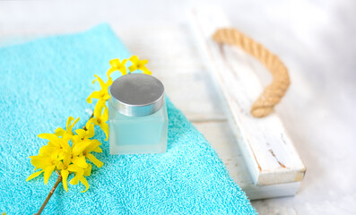 a jar of cream and a blooming branch with yellow flowers on an emerald towel. spa and freshness atmosphere - 780420011