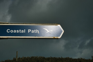 Coastal path sign pointing towards the beach on a stormy day