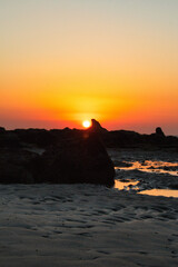 Vertical shot of sea waves hitting the rocky shore during a breathtaking sunset