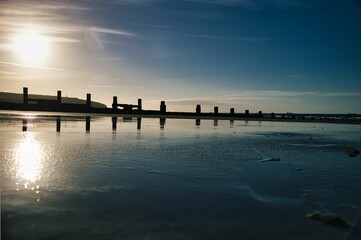 Beautiful view of the breakwater with reflection in the sea in Sandow bay, Isle of Wight at sunset - obrazy, fototapety, plakaty