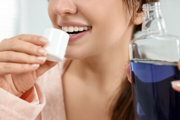 Young woman using mouthwash on blurred background, closeup