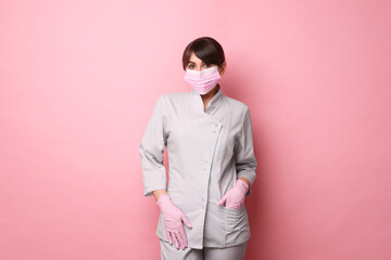 Cosmetologist in medical uniform on pink background