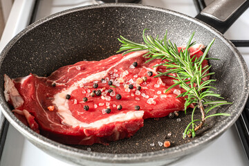 Beef steak sizzles in a frying pan on the stove, cooking to perfection