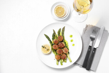 Delicious fried scallops with asparagus, lemon and thyme served on white table, flat lay. Space for text