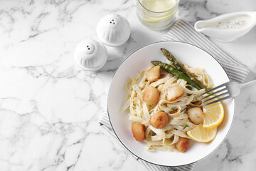 Delicious scallop pasta served on white marble table, flat lay. Space for text