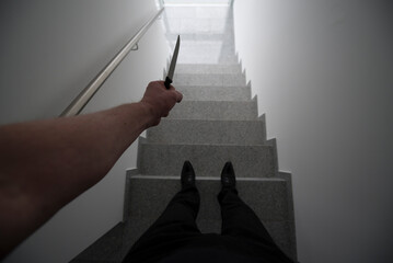 Personal Perspective on a Violent Man Holding a Knife in a Staircase with a Window Light in...