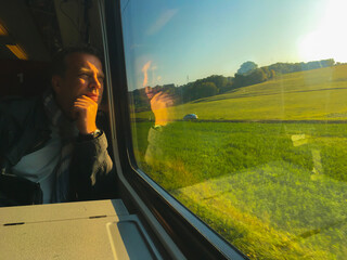 Man Travel in a Train and Looking Out at the Landscape in a Sunny Day in Vaud, Switzerland. - obrazy, fototapety, plakaty