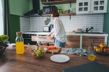 Caucasian cheerful young woman is engaged while spending time cooking in the kitchen