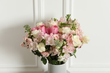 Beautiful bouquet of fresh flowers in vase near white wall