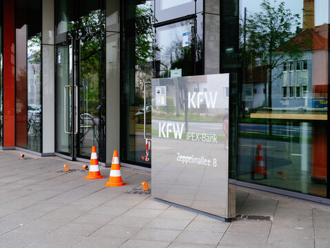 Frankfurt, Germany - Mar 31, 2024: Exterior of KFW IPEX Bank with a reflective glass door and safety cones placed outside, indicating cautionary measures