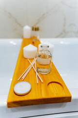 Wooden bathtub tray holding candles, water bottle, and napkin