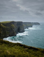 Scenic vertical view of the evergreen Cliffs of Moher in Ireland on a gloomy day