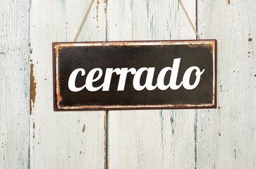Vintage tin sign on a wooden background - Closed in spanish
