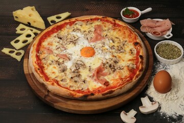 High angle shot of a gourmet pizza with various toppings on a messy kitchen table with ingredients