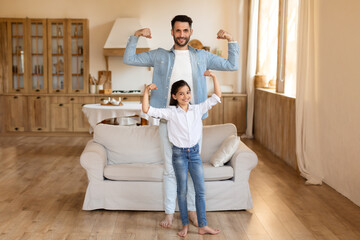 Father and daughter showing off muscles at home