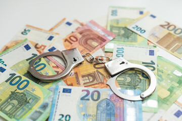 Police handcuffs lies on a set of green monetary denominations of 100 euros. A lot of money forms an infinite heap