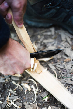 Cropped hands of man carving stick in forest