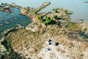 Beautiful aerial view of parked cars in a field on a shore of a lake
