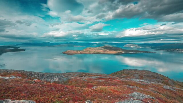 Stormy clouds above the fjord and tundra whirl in a timelapse video backlit by the sun, creating a stark contrast with the calm surroundings of autumn.
