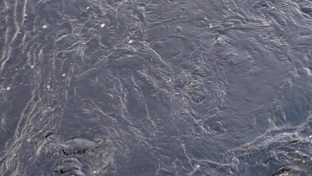 flowing water with chaotic patterns, eddy whirlpools and ripples
