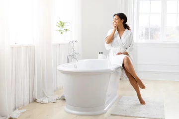 Tuinposter Woman touching face with foot dipped in bathtub © Prostock-studio