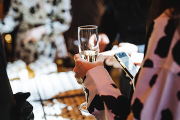 Woman holding glass of champagne and cell phone at event