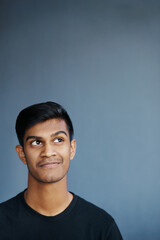 Obraz premium Thinking, idea and Indian man in studio for problem solving, brainstorming or solution on grey background. Why, planning and gen z student with how to, questions or reflection, memory or conclusion