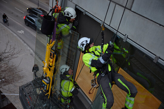 High angle view of rope access workers installing window glass of building